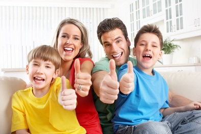 A family of four giving the thumbs up with smiles on their faces.